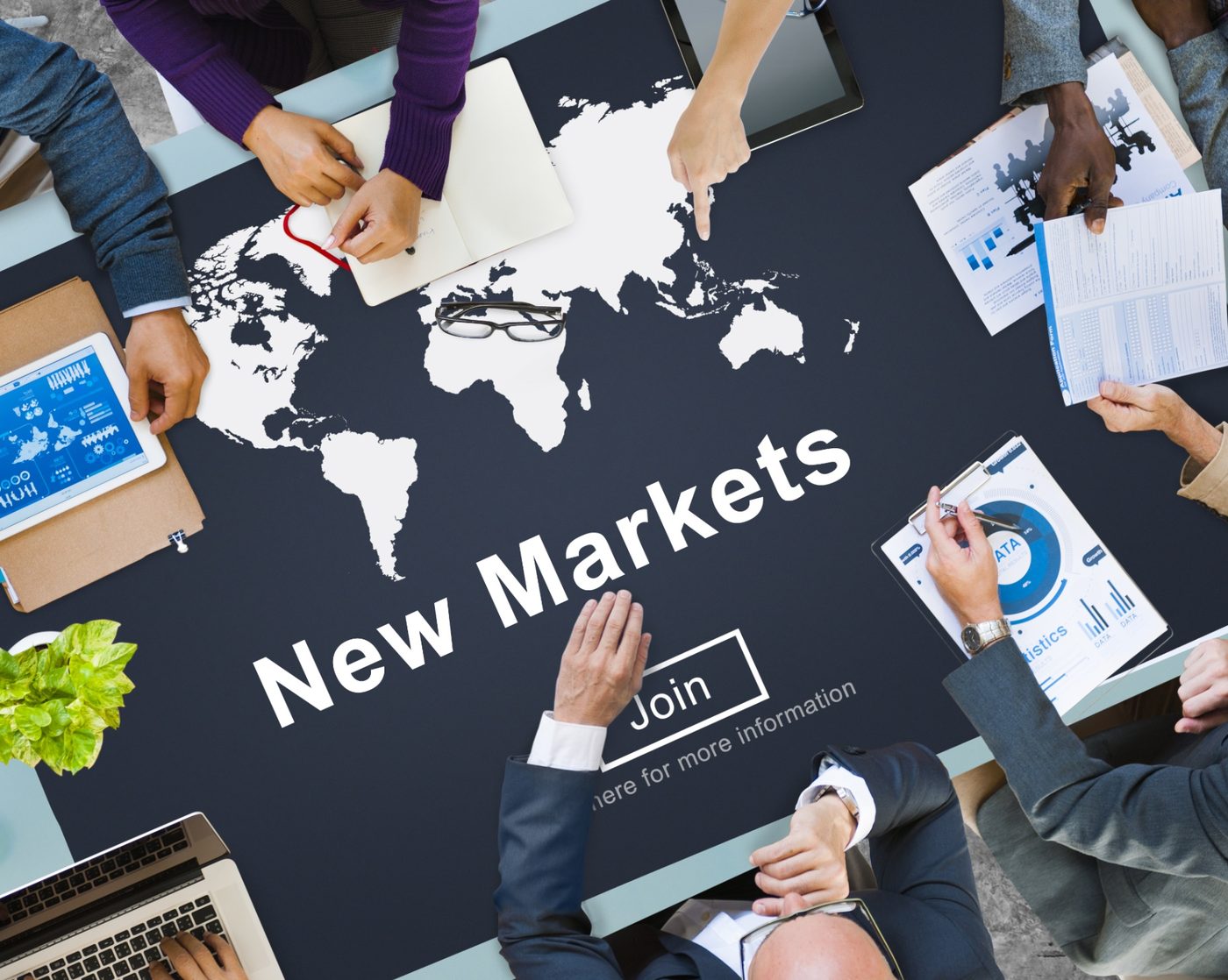A leadership team gathered around a world map, weighing new market opportunities.